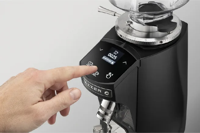 En finger trykker på berøringspanelet til Mazzer Mini Electronic, med dosetid i displayet