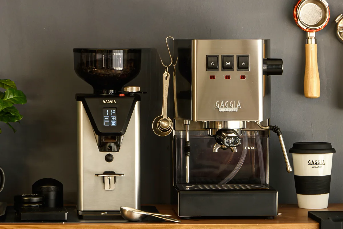 Gaggia Classic E24 i børstet stål på en trebenk ved siden av en Gaggia-kvern med display