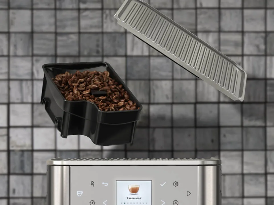 Den avtakbare bønnebeholderen løftet over en KitchenAid KF6 i rustfritt stål, med lokket svevende over