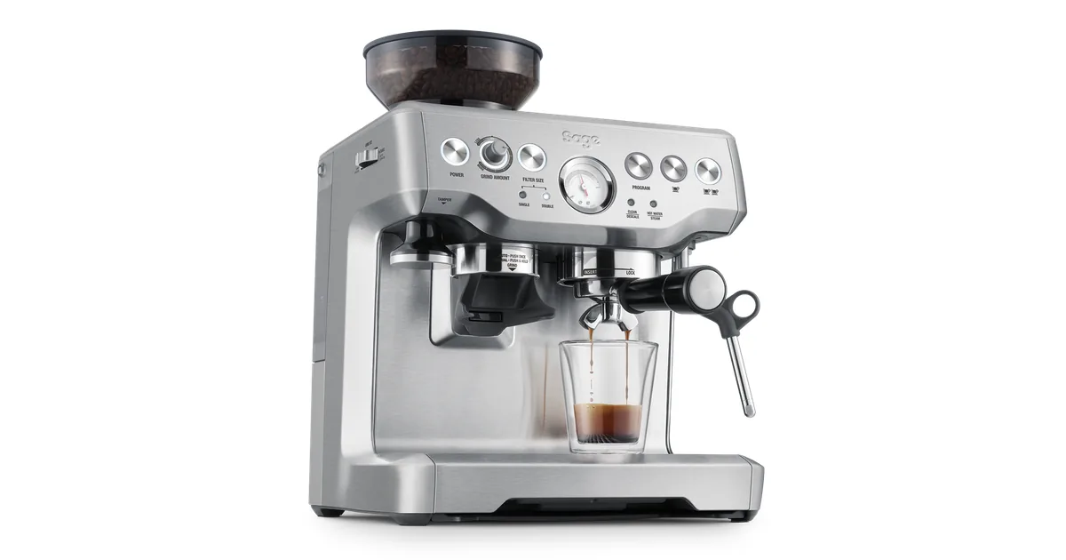 Sage Barista Express BES875 i børstet stål sett skrått forfra, med en espresso i glass under filterholderen