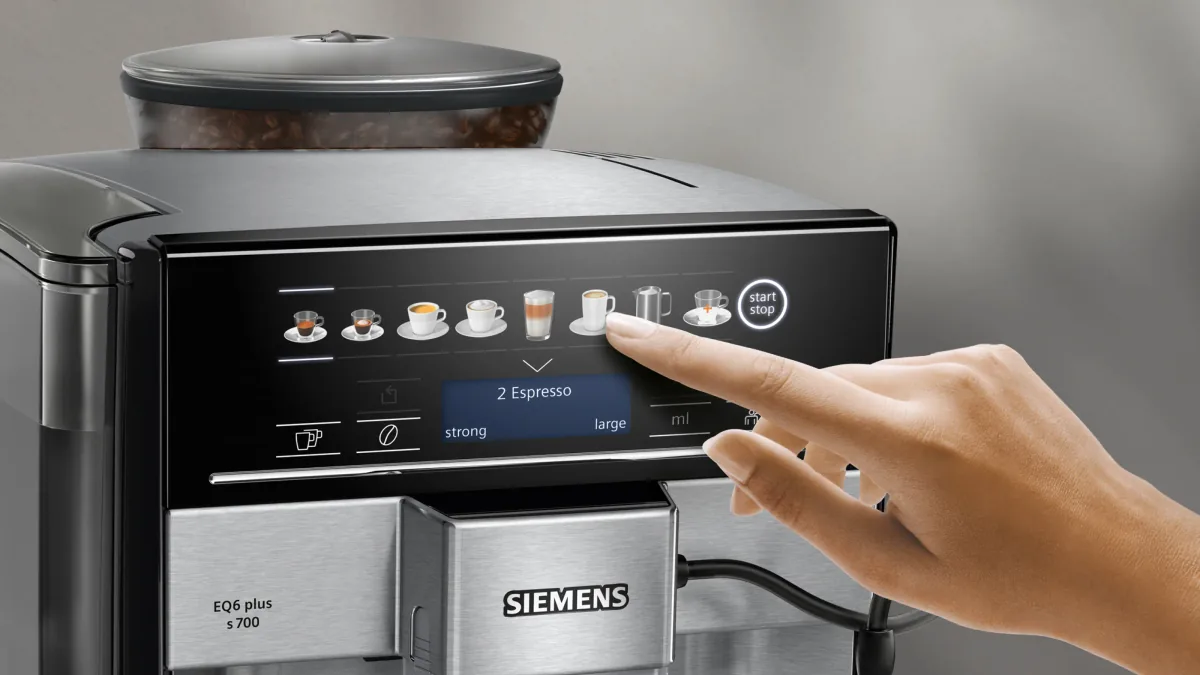 En finger trykker på panelet til Siemens EQ6 plus s700, med 2 Espresso i displayet