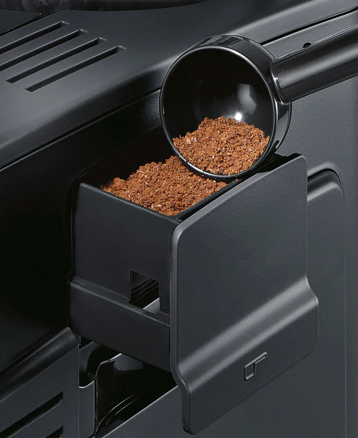 Den åpne skuffen for malt kaffe på siden av en Siemens EQ6 plus s100, med doseringsskjeen over