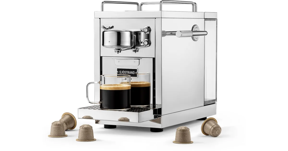 Sjöstrand The Original 2 i polert stål, sett skrått forfra, med to glass kaffe og kapsler rundt